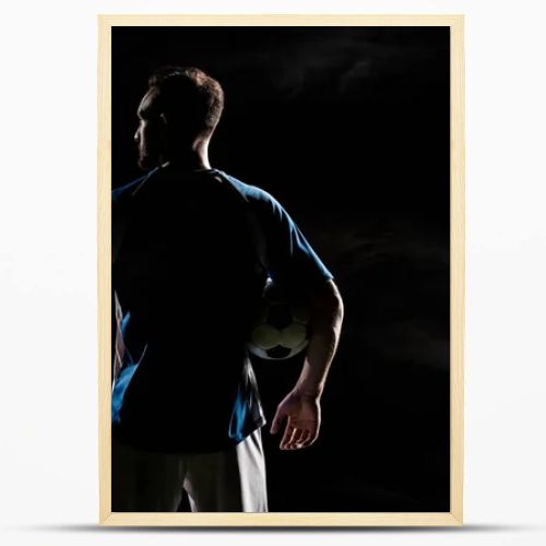 silhouette of football player standing with ball on black with smoke  