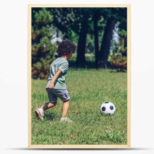 young african american father playing football with cute son in park