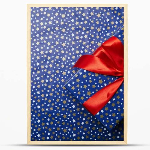 top view of wrapped gift box with red ribbon on festive wrapping paper with stars pattern