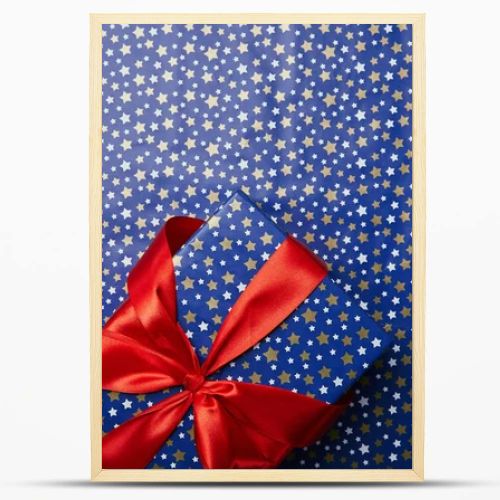 top view of wrapped gift box with red ribbon on festive wrapping paper with stars pattern