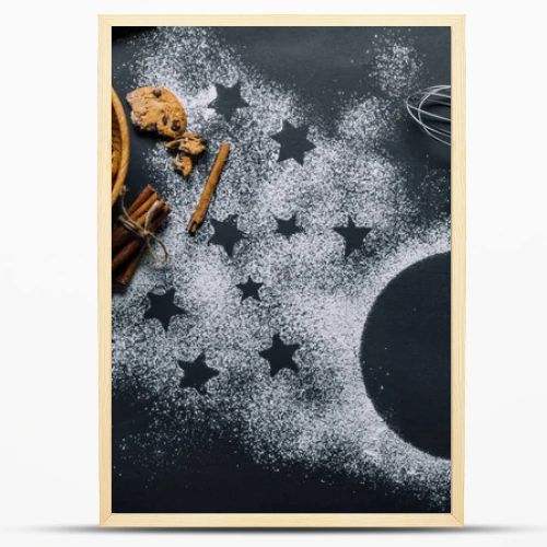view from above of cookies in bowl, whisks and rolling pin on table covered by flour with symbol of stars