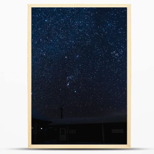 starry dark sky and houses covered with snow at night in winter