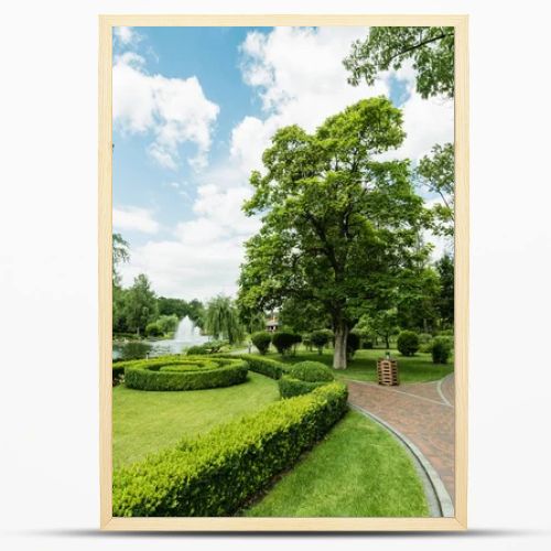 walkway near green plants, trees and fountains against blue sky 