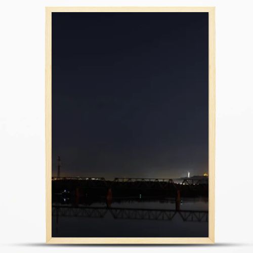 dark cityscape with tranquil river and bridge at night