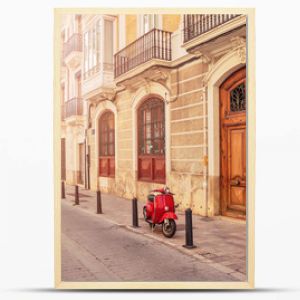 Spain. Valencia. A street in the tourist city of Valencia. Red motorcycle, moped. Tourist concept. Journey. Red vintage scooter parked on a sidewalk.