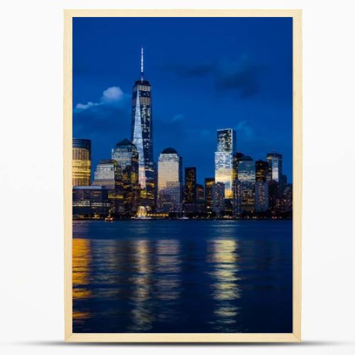 New York City Manhattan downtown skyline with skyscrapers illuminated over Hudson River panorama, including the One World Trade Center