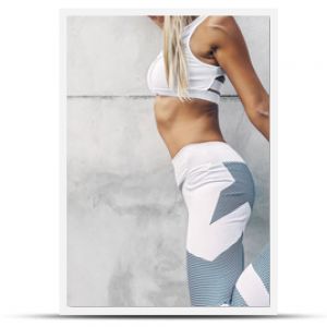 Model sportowy fitness w modnej odzieży sportowej pozowanie na szarej ścianie