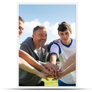 Team of young football players stacking hands before match