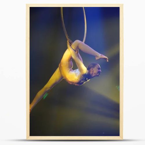 Flexible young woman make performance on aerial hoop, yellow light, flexible split on aerial hoop, aerial circus show, excellent stretching