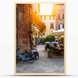 Old cozy street with tables of restaurant in Lucca, Italy