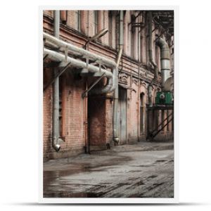 Stary widok na ulicę przemysłową z fasadami i rurami z czerwonej cegły