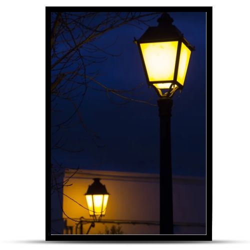 Traditional european streetlight pole lit at night