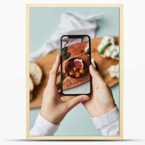 Top view of young woman taking aesthetic photo of food using smartphone in home studio, copy space