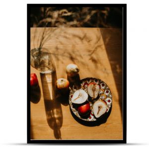 still life with a bottle. pears on a wooden table. pears on a wooden table bathed in the sun. picnic in the summer garden. flowers and fruits on a wooden table. sunny shadows on the kitchen table