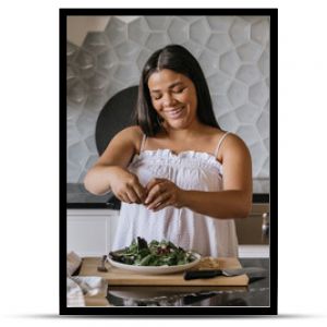 Young adult woman preparing salad for lunch in luxury kitchen