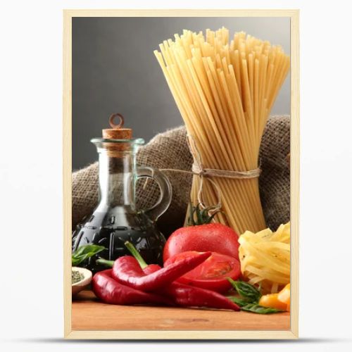 Pasta spaghetti, vegetables and spices, on wooden table, on grey background