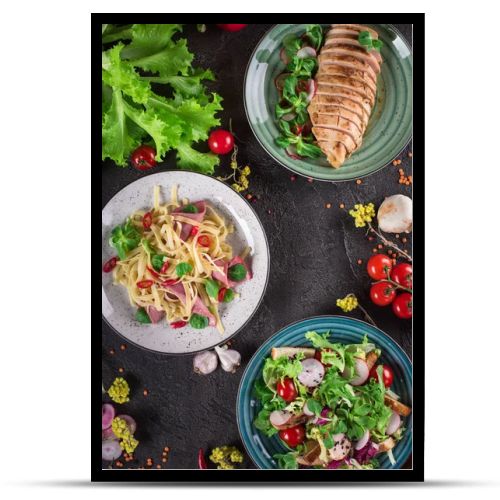 Delicious dinner. Italian pasta, fresh vegetable salad and roasted chicken breast on the black background. Healthy food. Close up. Top view