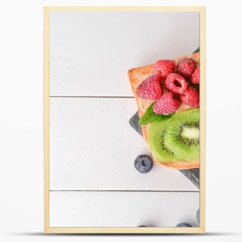 Slate plate with tasty sandwiches, kiwi and berries on white table