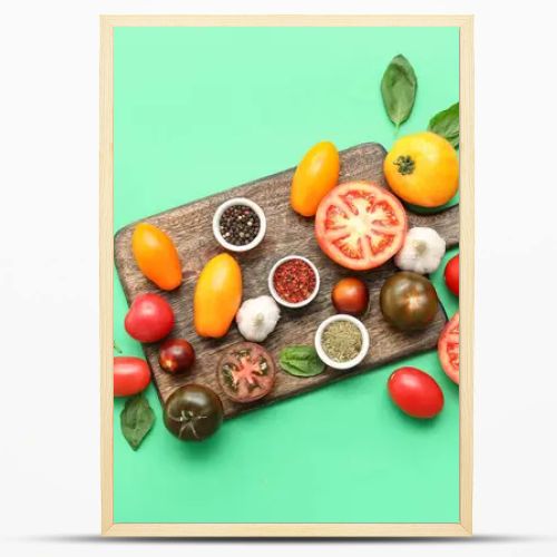 Wooden board with fresh ripe tomatoes and different spices on green background