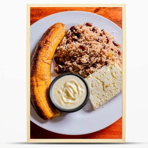 Gallopinto plate with cheese and maduro on wooden table. Nicaraguan food concept, Traditional Gallo Pinto meal with maduro and cheese served