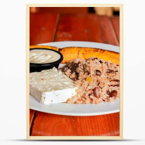 Traditional Gallo Pinto meal with maduro and cheese served. Gallopinto plate with cheese and maduro on wooden table. Nicaraguan food concept