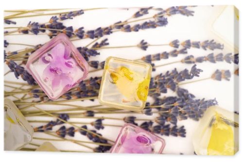 top view of floral and fruit ice cubes and lavender twigs on white surface