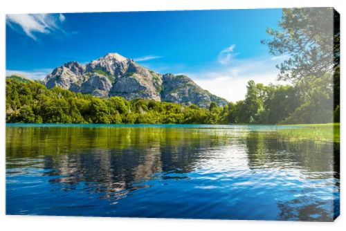 Lake with clear water green grass on the coast and reflected mountain. Argentina