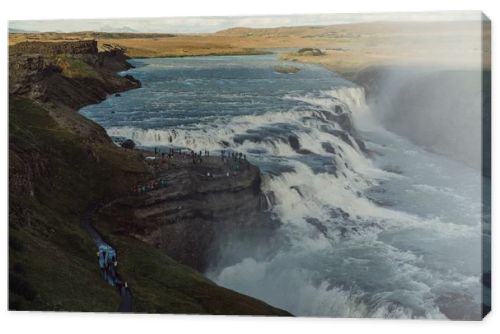 group of tourists looking at majestic waterfall in Iceland 