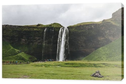 ICELAND - 20 JUNE 2018: beautiful waterfall Seljalandsfoss and tourists under cloudy sky 