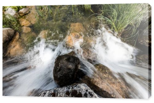top view of water flowing on rocks near grass in park 
