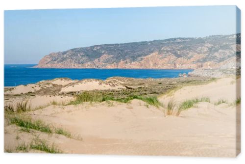 Soft sand dunes with sparse grass leading toward the Atlantic Ocean horizon near Guincho Cascais Portugal.