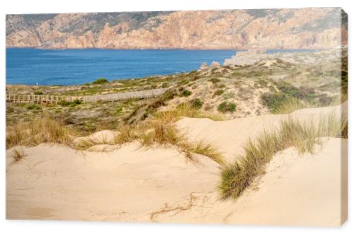 Soft sand dunes shaped by coastal wind with sparse grass above the Atlantic shoreline near Guincho Cascais Portugal.