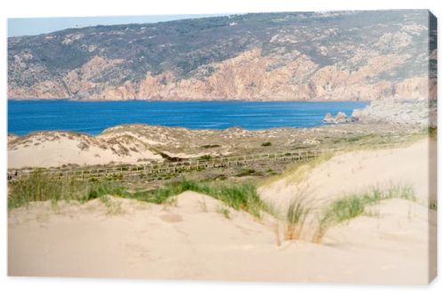 Rolling sand dunes with coastal grass and open Atlantic Ocean views along the Guincho coastline near Cascais Portugal.