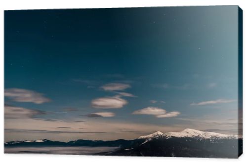 scenic view of snowy mountains with white fluffy clouds in evening