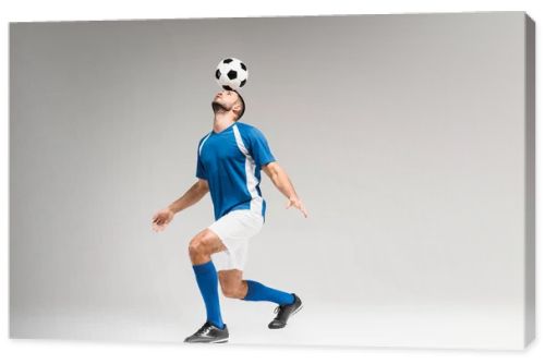 Sportsman holding football on head while balancing on grey background 