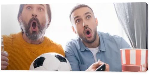 excited interracial father and son watching football championship at home, banner