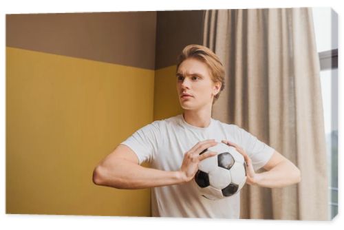 young handsome man holding football at home, end of quarantine concept