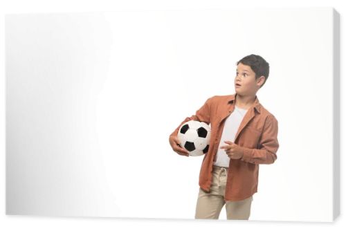 shocked boy holding soccer ball, looking away and pointing with finger isolated on white