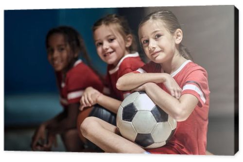 Smiling girl with soccer ball  in good mood  before training  in changing room.