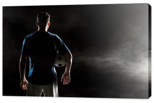 silhouette of man standing in uniform with ball on black with smoke  