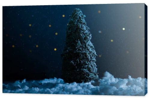 close-up shot of miniature christmas tree standing in snow in night