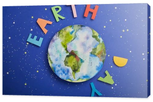 top view of colorful paper letters and planet picture on violet background with stars, earth day concept