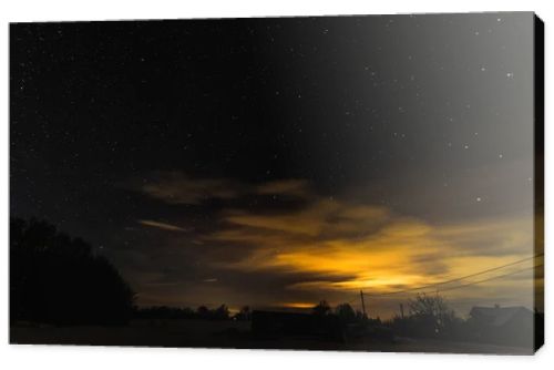 starry dark sky and yellow light in carpathian mountains at night in winter