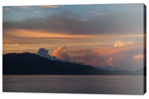 hill silhouette with dark water surface under cloudy sunset sky