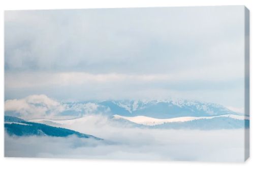 scenic view of snowy mountains in white fluffy clouds