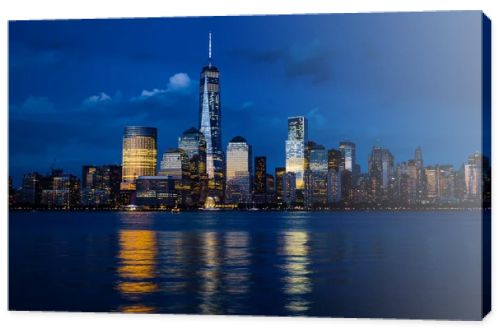 New York City Manhattan downtown skyline with skyscrapers illuminated over Hudson River panorama, including the One World Trade Center
