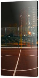 Oświetlony plac zabaw do koszykówki z czerwonym chodnikiem, nowoczesną siatką do koszykówki i flarami obiektywu w tle