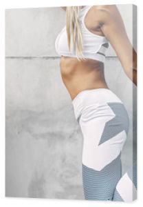 Model sportowy fitness w modnej odzieży sportowej pozowanie na szarej ścianie