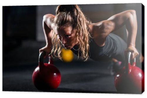 Woman athlete exercising with kettlebells indoors