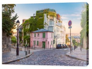 Przytulna stara ulica z różowym domem w słonecznej dzielnicy Montmartre o wschodzie słońca w Paryżu we Francji